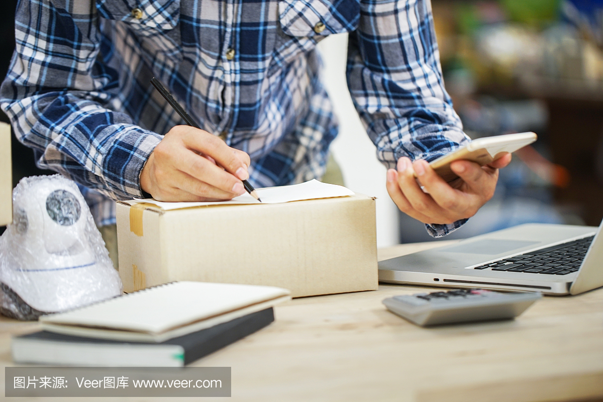 年輕的創(chuàng)業(yè)小企業(yè)主在工作場所的盒子里裝攝像頭閉路電視。自由職業(yè)者銷售者準備產品的包裝過程在家里。網絡銷售,網絡營銷,